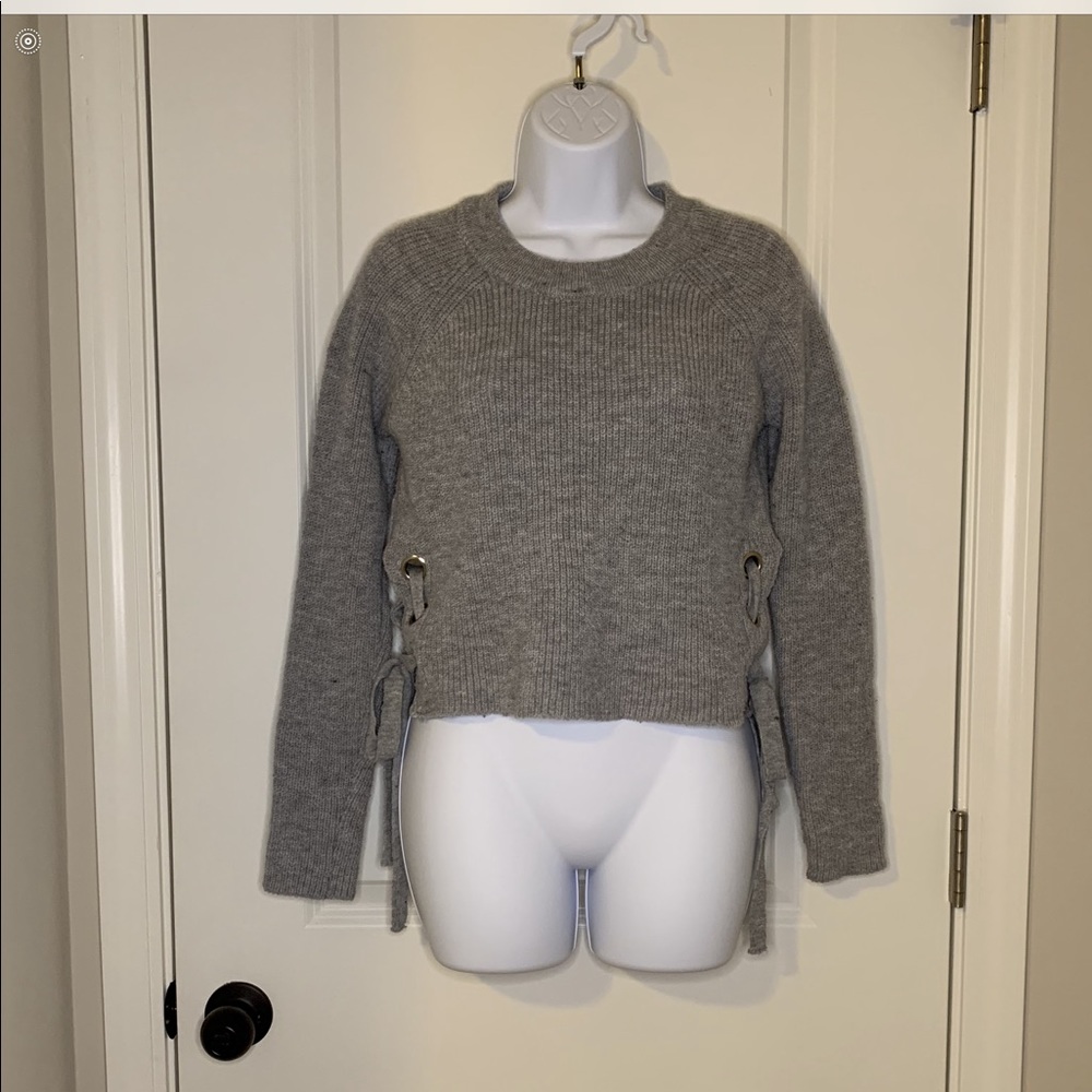 Gray cropped sweater with ties on the sides.